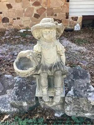 Weathered concrete girl statue holding a basket