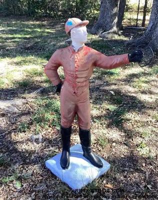 A garden statue of a jockey in full racing attire