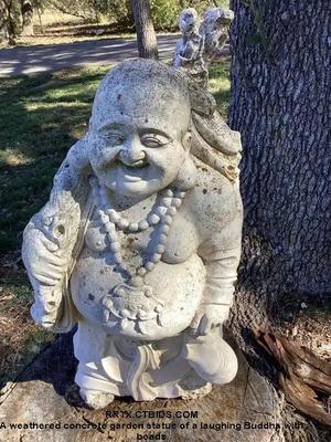 A weathered concrete garden statue of a laughing buddha with beads