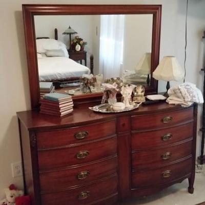 Dresser with mirror, lamp, books, vanity items
