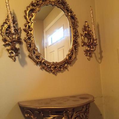 Ornate framed mirror, wall sconces and shelf