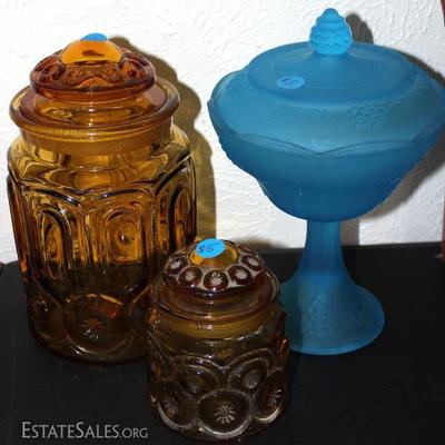 A pair of brown glass lidded jars with a blue glass lidded jar
