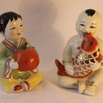 Two porcelain children figures holding coy & fruit
