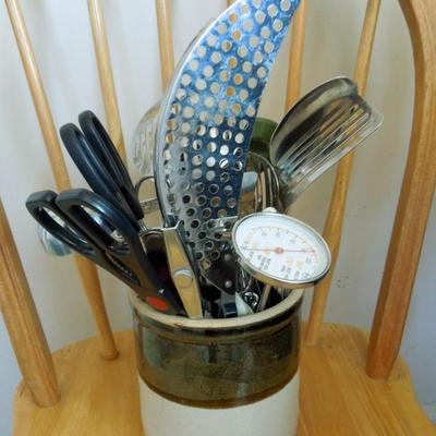 Old crock with assortment of kitchen utensils.