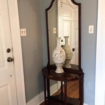 Entry hall valet with table and mirror and some sculpted pottery.