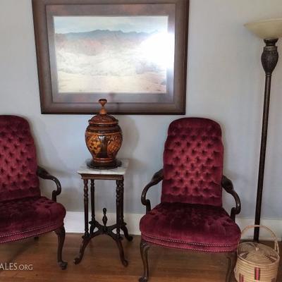 Red chair pair, large hand-carved wooden urn, and a marble-top side table or plant stand.