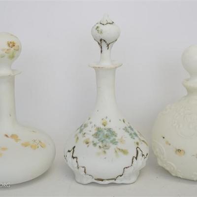 Three Antique Milk Glass Barber Bottles. Two with embossed Floral and Filigree and one smooth. Tallest 10 1/2