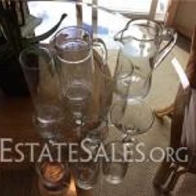 
065: Miscellaneous Glassware  Collection of glassware in different styles, two tall glass vases and two glass pitchers, one looks hand...