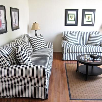 Black and White stripe sofa and settee, glass top coffee table, end tables, lamps, framed prints, and area rug.