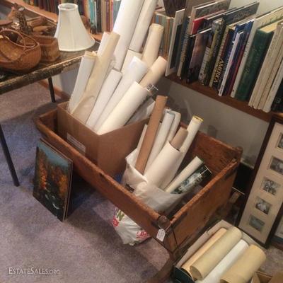 Unframed posters leaning inside of an early 19th century American cradle made of pine