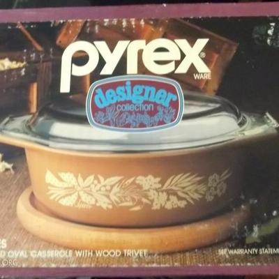 Un opened Pyrex promotional covered casserole with wood trivet.