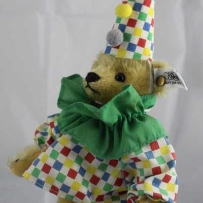 Steiff - Circus Clown Driver-183 in the box.   Checked cone hat with red, green, yellow, and blue  pom poms.  Green ruffle around neck....