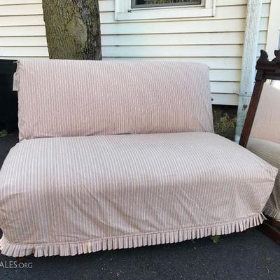 Slipcovered love seat/settee with white muslin upholstery underneath.