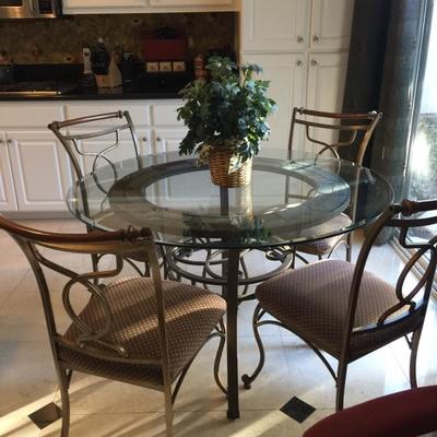 Beautiful round glass table with iron base and 4 chairs - part of the kitchen 
