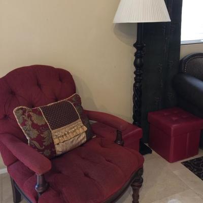 Red chair with tall standing lamp and two little red ottomans with storage part of living room 