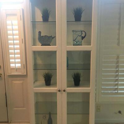 tall white cabinet w/ glass doors and glass shelves
