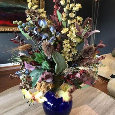 Elegant silk floral arrangement with warm palette of
colors in a blue glass vase