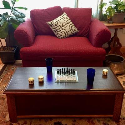 Red-patterned love seat, copper pot, glass chess set, live plants, tea lights