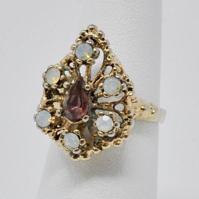 Costume ring with purple center stone, and six opal-like stones surrounding it. Gold plated.