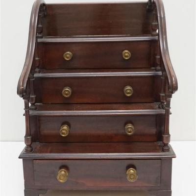 English Mahogany Miniature Chest of Drawers. Of step form, having scroll finger roll rail with spindles, five graduated recessed hand...