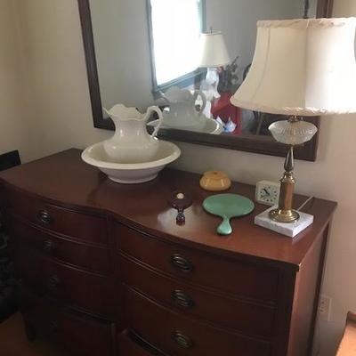 Dresser with pitcher and bowl and lamp.