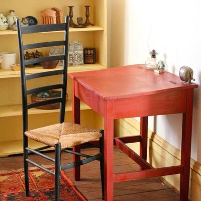 wood student desk with lift top, ladder back chair, tribal rug, bookshelves, and collectibles