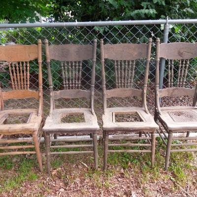 Set of four weathered antique pressed wood farm chairs in need of repair.