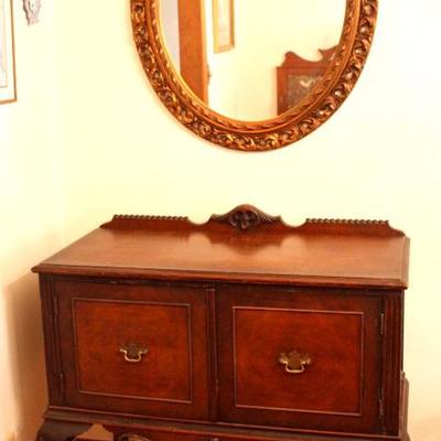 oval mirror in gold frame and side board