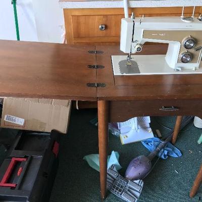 Old sears electric sewing machine attached to vintage sewing table.  Includes a bag of various machine accessories.