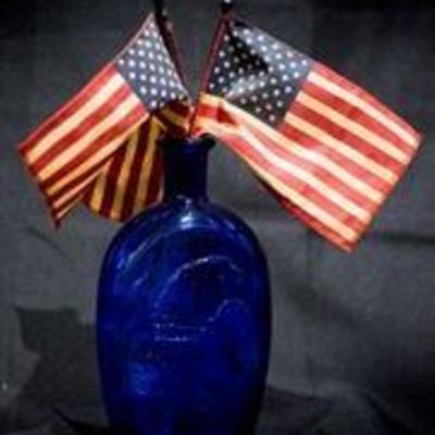 8.5â€³ x 8â€³ | Folk Art |  Two Blue Glass Vases | Three Mini American Flags
This folk art set consists of two blue glass vases made...