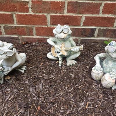 Outdoor trio of frog band members sculptures.