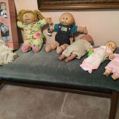 Variety of antique dolls, vintage bench 