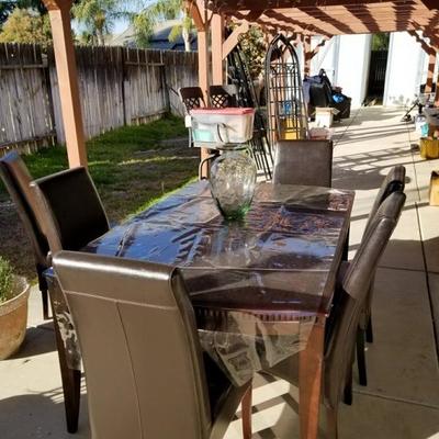 Beautiful modern dining table with leather chairs used outside in yard area 