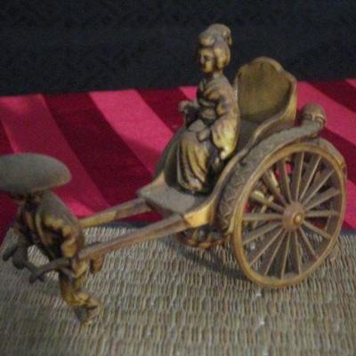 Vintage miniature lady being carried in a cart by two men front and back