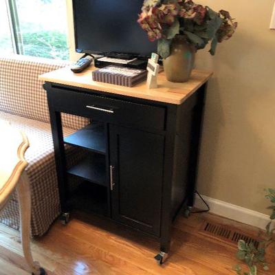 Rolling cart with butcher block top and small TV.