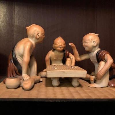 Whimsical Asian Figurines playing Game on a stand 