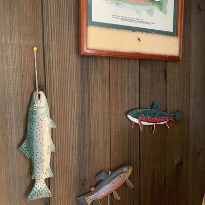 Three carved fish decoys and a framed print of a rainbow trout  
