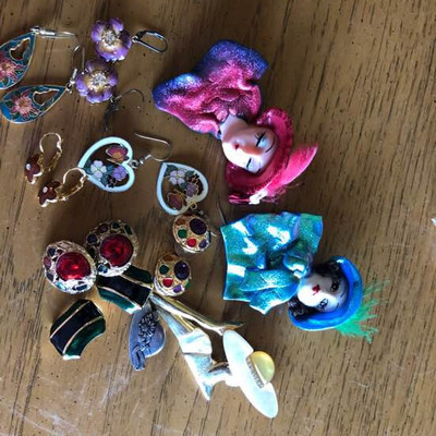 A collection of earrings and red hat lady pins