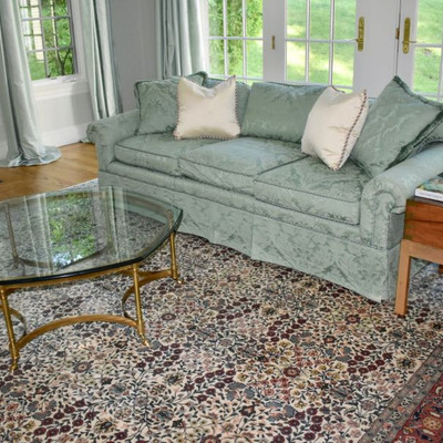 Green damask sofa and one of a pair of glass and brass occasional tables