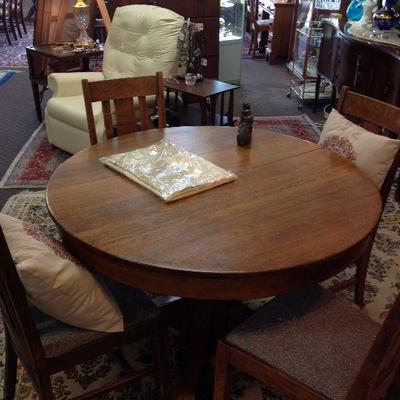 Traditional round oak dining table w/ 2 leaves & 4 chairs.