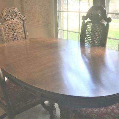 Beautiful Italian Baroque dining table with two leaves and pads.  Has chairs with cane back and upholstered seats.  Matching 2 arm chairs