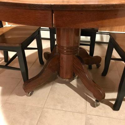 Oak pedestal table with black chairs