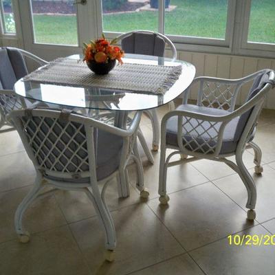 White Rattan Glass top Table with 4 chairs on casters.