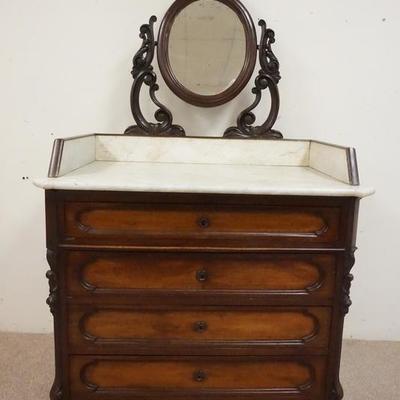 1027	WALNUT VICTORIAN MARBLE TOP WASHSTAND. HAS AN INSET MARBLE AND WALNUT SPLASH AND AN OVAL MIRROR IN A CARVED FRAME. 4 DRAWERS
