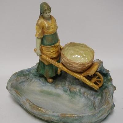 1029  AMPHORA FIGURAL TRAY. WOMAN WITH A WHEEL BARROW. SIGNED UNDER GLAZE AMPLORA AUSTRIA WITH A CROWN, 4864. 13 IN WIDE, 11 3/4 IN HIGH

