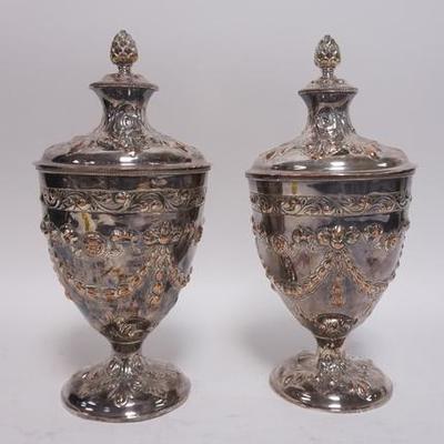 1189	PAIR OF ORNATE SILVER ON COPPER COVERED URNS, SOME WEAR TO THE SILVER PLATE, 14 IN H 
