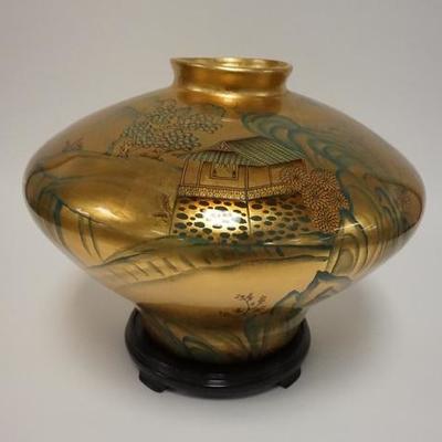 1002	LARGE SCENIC ASIAN VASE, HAND PAINTED ON A GOLD BACKGROUND. COMES WITH CARVED WOODEN BASE. 12 3/4 H. APP 17 IN DIAMETER

