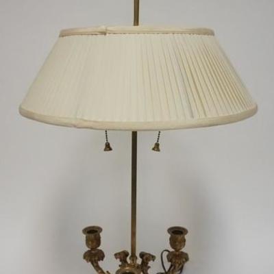 1007	BRASS TABLE W/ CANDLE HOLDERS & RAMS HEAD DECORATION COMES W/ A PLEATED CLOTH SHADE, 31 IN H 
