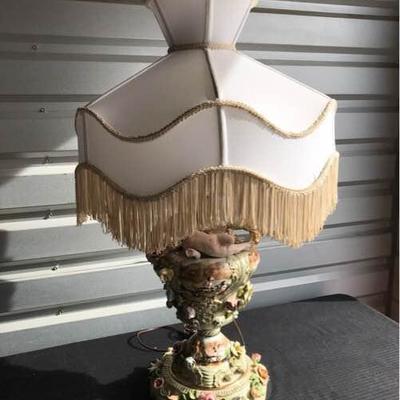 Vintage Porcelain Lamp with flowers and cherubs with original fringed lampshade and in good working condition. Made in Italy late...