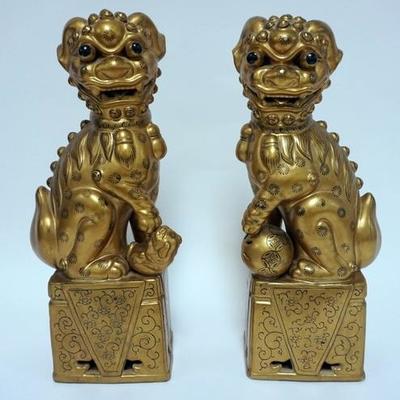 1002	PR OF GILT CERAMIC FOO DOGS WITH BLACK PAINTED DECORATION. ONE HAS A REPAIR. 14 3/4 IN H
